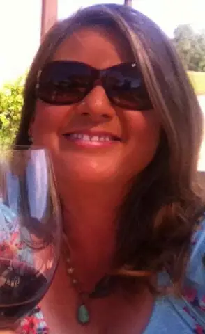 Lisa Rush smiling and holding a glass of wine.